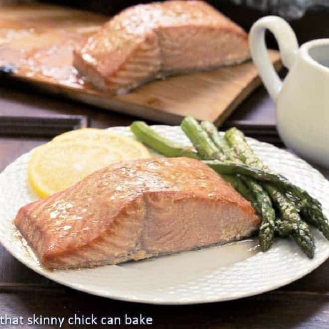Grilled Cedar Plank Salmon flavored with a simple marinade then grilled for an elegant tasty seafood entree! Grilled Cedar Plank Salmon on a white plate with asparagus