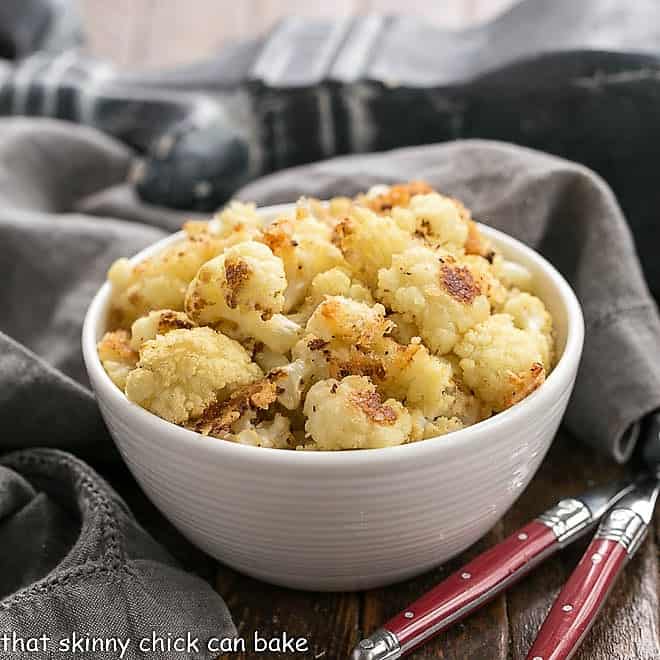 Roasted Cauliflower in a white bowl with two red handled forks