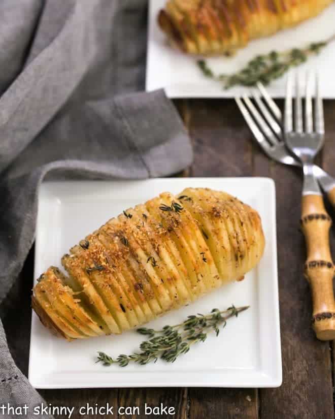 Hasselback Potatoes on square white ceramic plates with bamboo forks