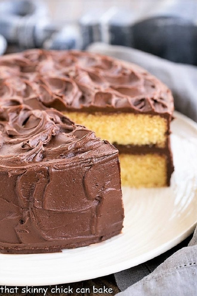 Perfect Yellow Cake Recipe with Chocolate Buttercream on a white cake plate with a slice removed