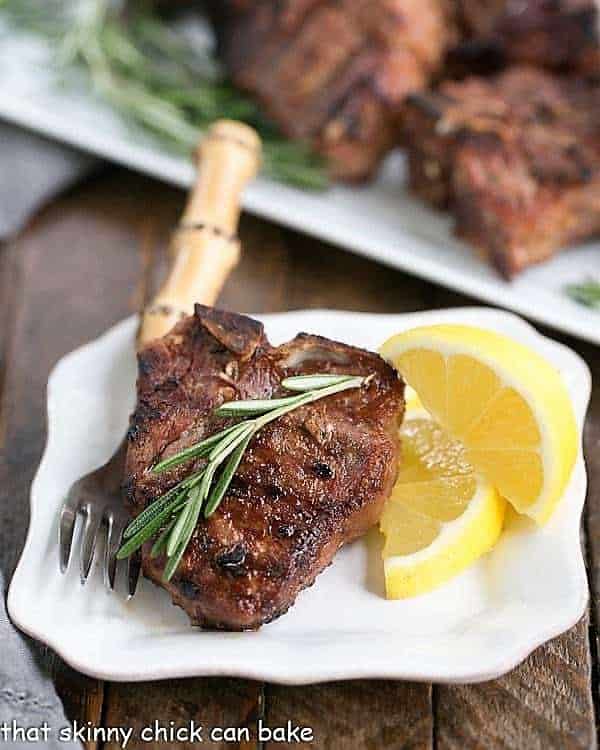 Grilled Lamb Chops with Mustard, Rosemary and Garlic on a small white plate with a sprig of rosemary and lemon wedges. Grilled Lamb Chops with Mustard, Rosemary and Garlic on a small white plate with a sprig of rosemary and lemon wedges.