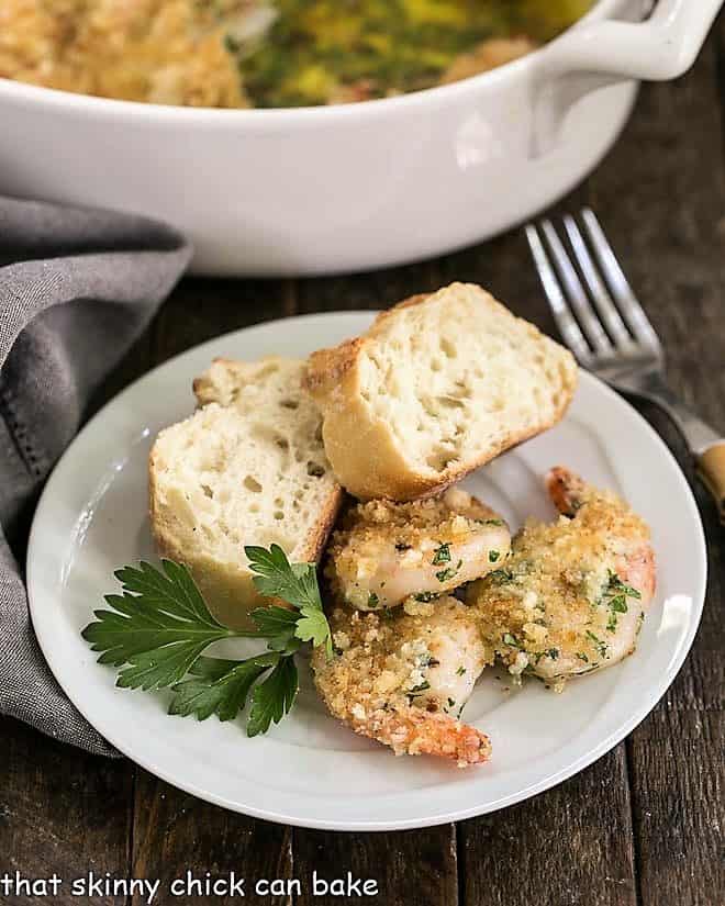 Baked Garlic Shrimp - topped with bread crumbs and cooked in spicy, garlic butter, this easy recipe is perfect for dinner any night of the week! Baked Garlic Shrimp with bread on a small white plate with a bamboo handled fork