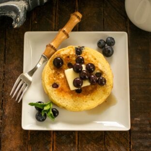 Overhead view of buttermilk pancakes with blueberries on a white plate.