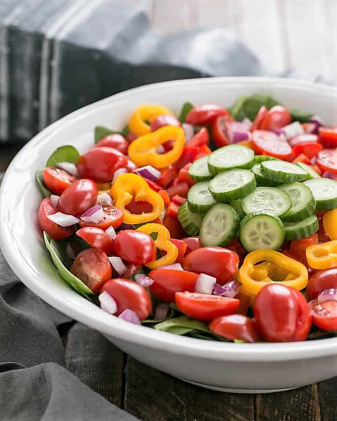Gazpacho Spinach Salad - a refreshing vegetable salad with a piquant red wine vinaigrette Undressed Gazpacho Spinach Salad in a white ceramic serving bowl.