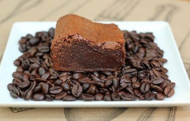 These Fudgy Kahlua Brownies - rich, dense, even a bit gooey. Brownie perfection in every bite! Kahlua Brownies on a white plate covered with coffee beans