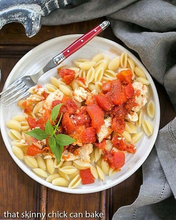 Chicken Feta Casserole - A fabulous casserole chock full of tomatoes, garlic, feta and herbs! Chicken Feta Casserole from above on a white plate with a red handled fork.