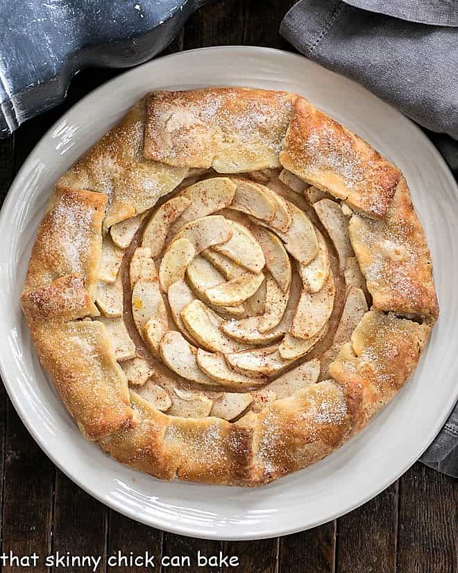 This scrumptious Apple Galette is a gorgeous, impressive dessert. This rustic apple tart has all the delicious flavors of a pie without all the effort! Overhead Rustic Apple Galette on a white plate.