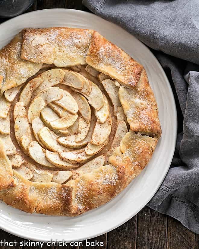 This scrumptious Apple Tart is a gorgeous, impressive dessert, So easy to make and all thefabulous autumn flavors of an apple pie recipe! Partial view of Apple Tart from above on a white serving plate.