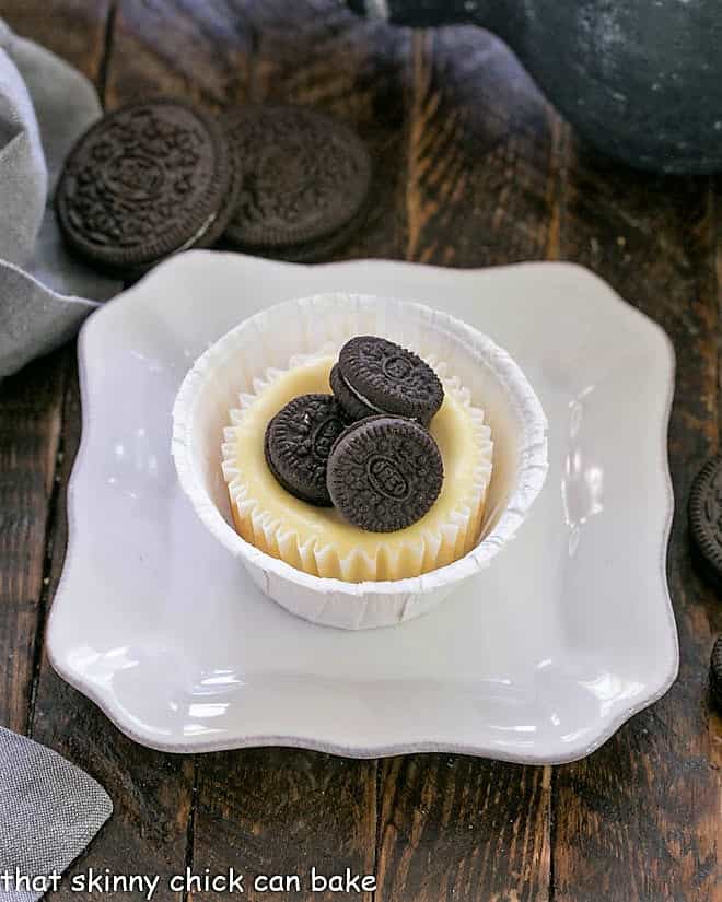 One Oreo cheesecake topped with 3 mini oreos on a square white plate