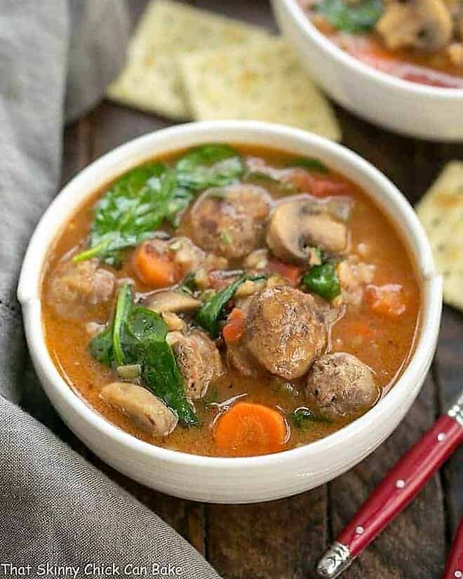 Comforting, rustic farro soup with a taste of Italy in every spoonful Rustic Farro Soup in a white soup bowl with a red handled spoon.