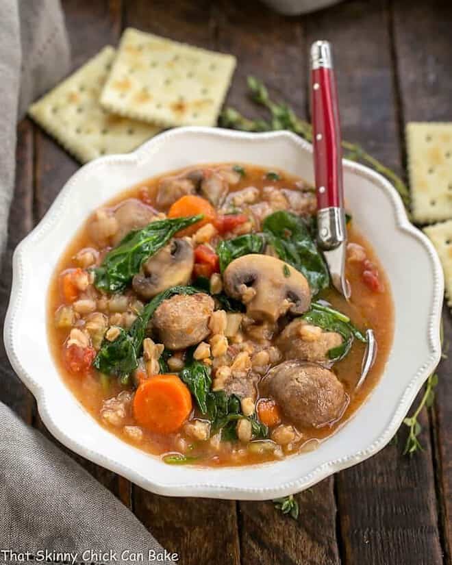 Comforting, rustic farro soup with sausage and a taste of Italy in every spoonful Rustic Farro Soup in a scalloped soup bowl with a spoon.