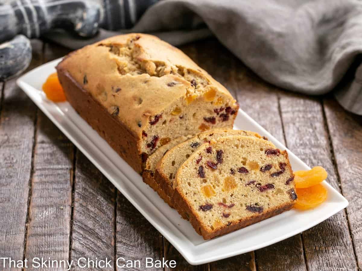 Apricot Quick Bread - a tender loaf packed full of dried fruit Cranberry Apricot Bread on a white tray with dried apricot garnish.