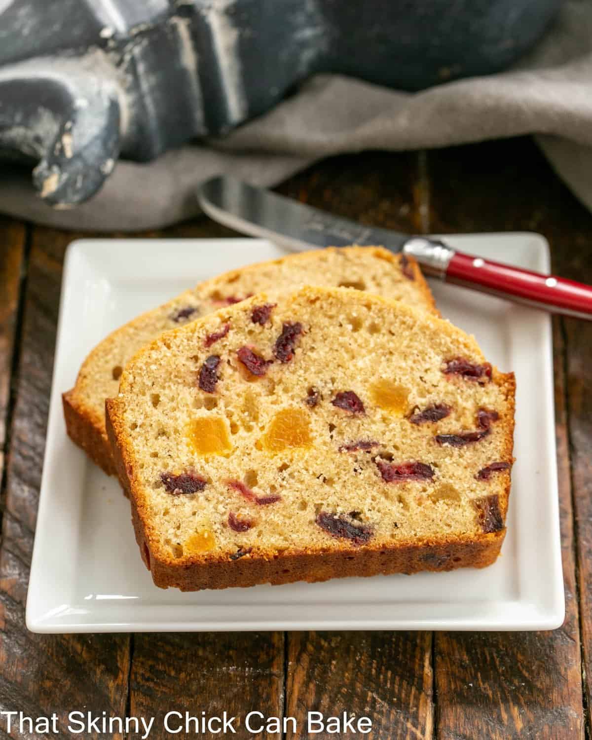 Apricot Quick Bread - a tender loaf packed full of dried fruit 2 slices of apricot bread on a square white plate with a red handle knife.