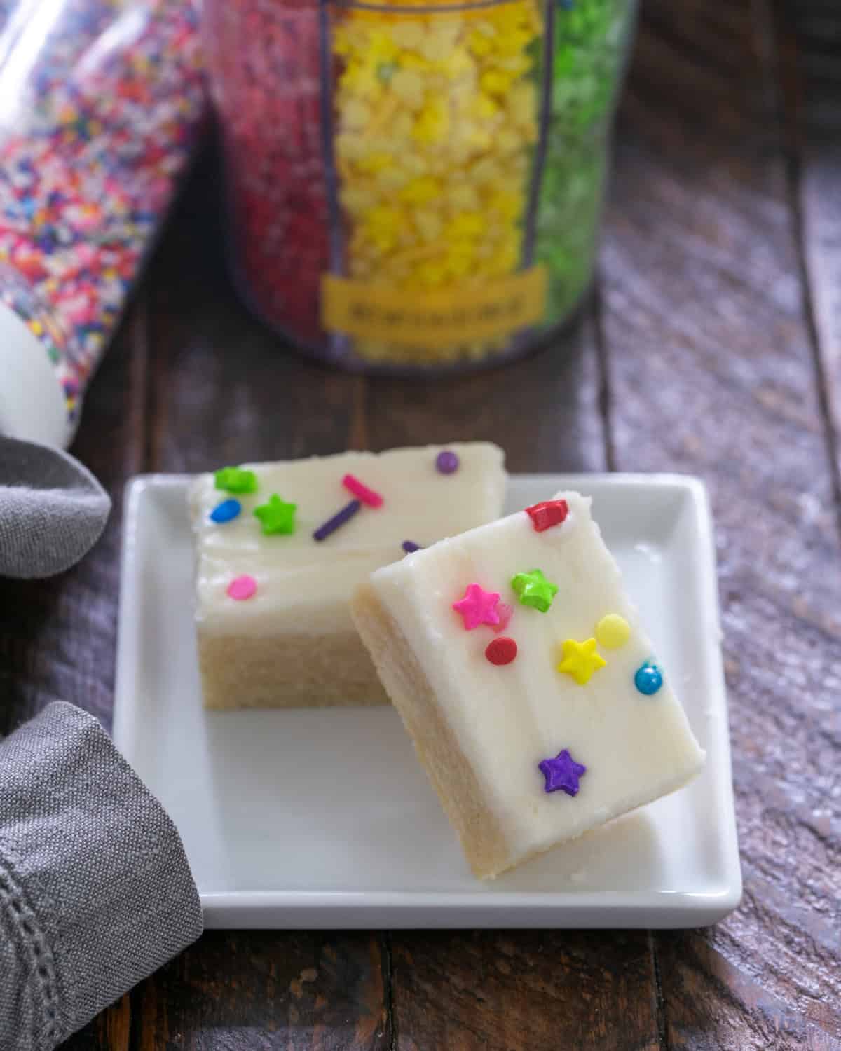 2 Frosted sugar cookie bars on a small white plate.