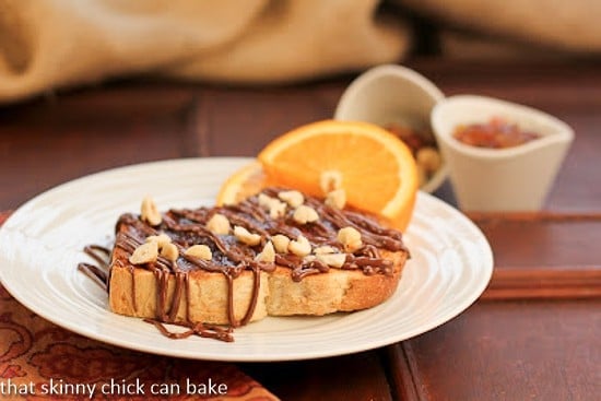 Nutella Tartine sprinkled with chopped hazelnuts on a white plate