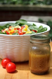 Gazpacho Spinach Salad - a refreshing vegetable salad with a piquant red wine vinaigrette Gazpacho spinach salad in a white serving bowl with a mason jar of salad dressing.