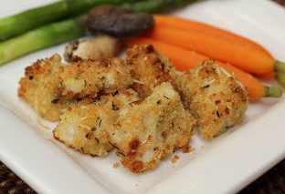 Baked chicken nuggets on a square white plate with vegetables