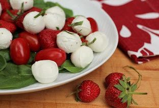 White oval platter of mozzarella, tomato and strawberry salad