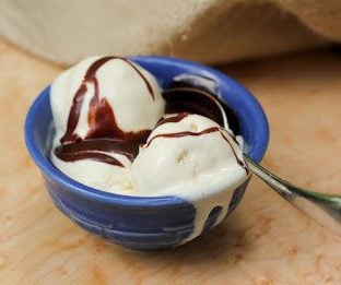 Marshmallow ice cream with a drizzle of hot fudg e in a blue bowl