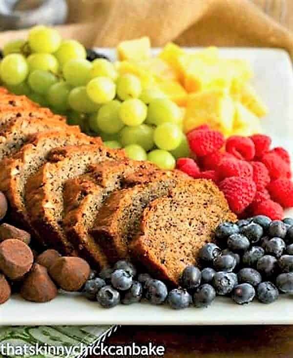 Moist Banana Bread Recipe - Tender and delicious with brown butter and pecans! Tray of sliced Nutty Brown Butter Banana Bread with fruit.