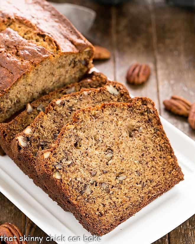 The Best Banana Bread - Perfect brunch, breakfast or snack with the nutty taste of brown butter and pecans.! Brown Butter Banana Bread slices on a white ceramic tray.