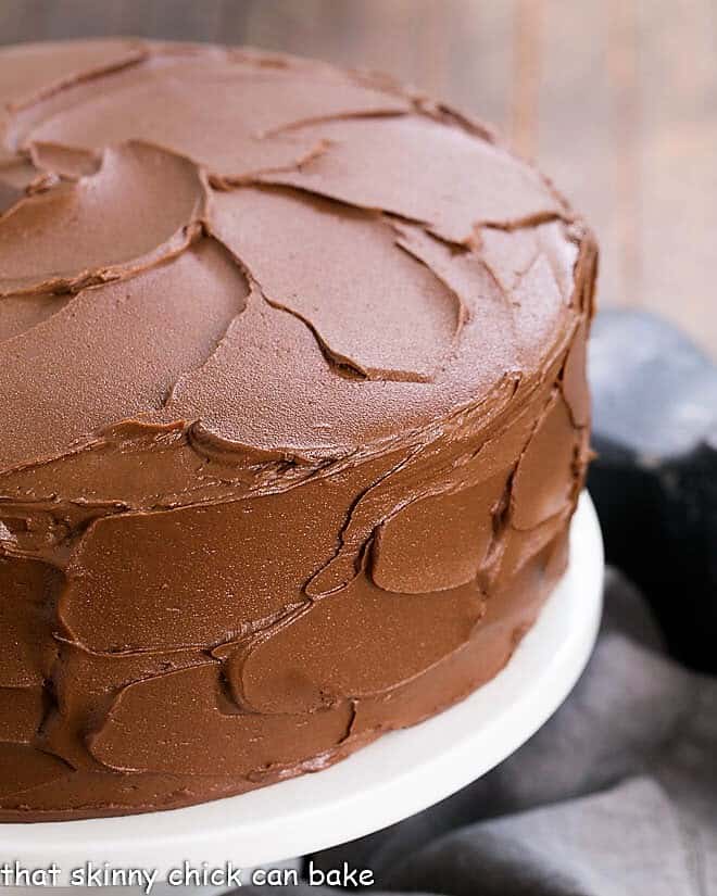Chocolate Layer Cake Filled with White Chocolate Ganache - a rich chocolate cake from scratch for dark and white chocolate lovers Chocolate Layer Cake with Ganache on a white ceramic cake stand.