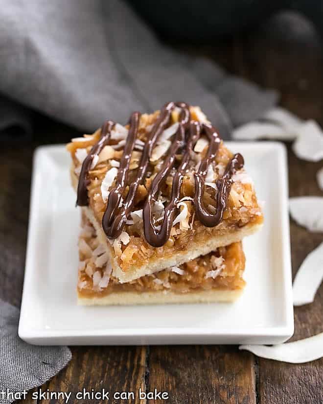 Homemade Samoa Bars - all the same terrific flavors of the classic Girl Scout Cookies with a shortbread base, caramel and coconut topping and chocolate drizzle! Homemade samoa bars stacked on a white plate.