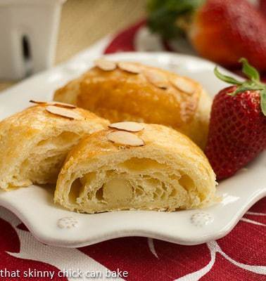 Almond croissants on a white plate with a fresh strawberry