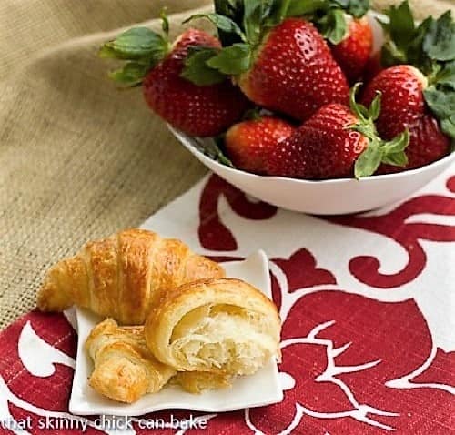 Homemade Classic Croissants - Heavenly, tender, flaky and buttery results! Homemade Classic Croissants with one broken open on a white plate with strawberries.