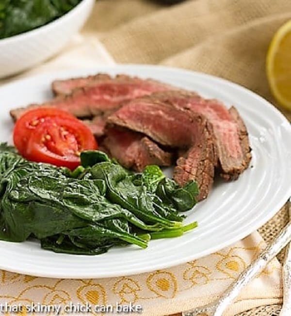 Easy Lemon Spinach with flank steak on a white plate