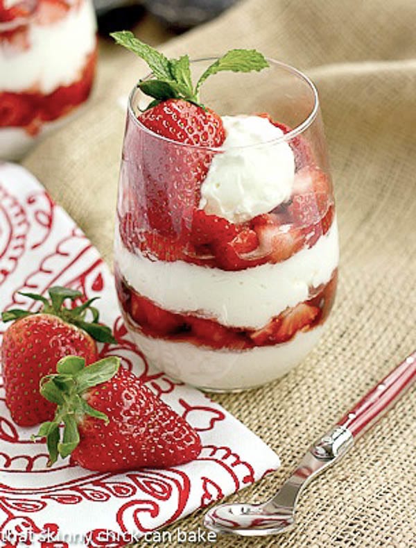 No-Bake Strawberry Cheesecake Parfaits - sweet luscious berries layered with dreamy cheesecake and topped with a dollop of cream for a beautiful, tasty treat! Strawberry Parfaits with a red handled spoon, red and white napkin and fresh strawberries.
