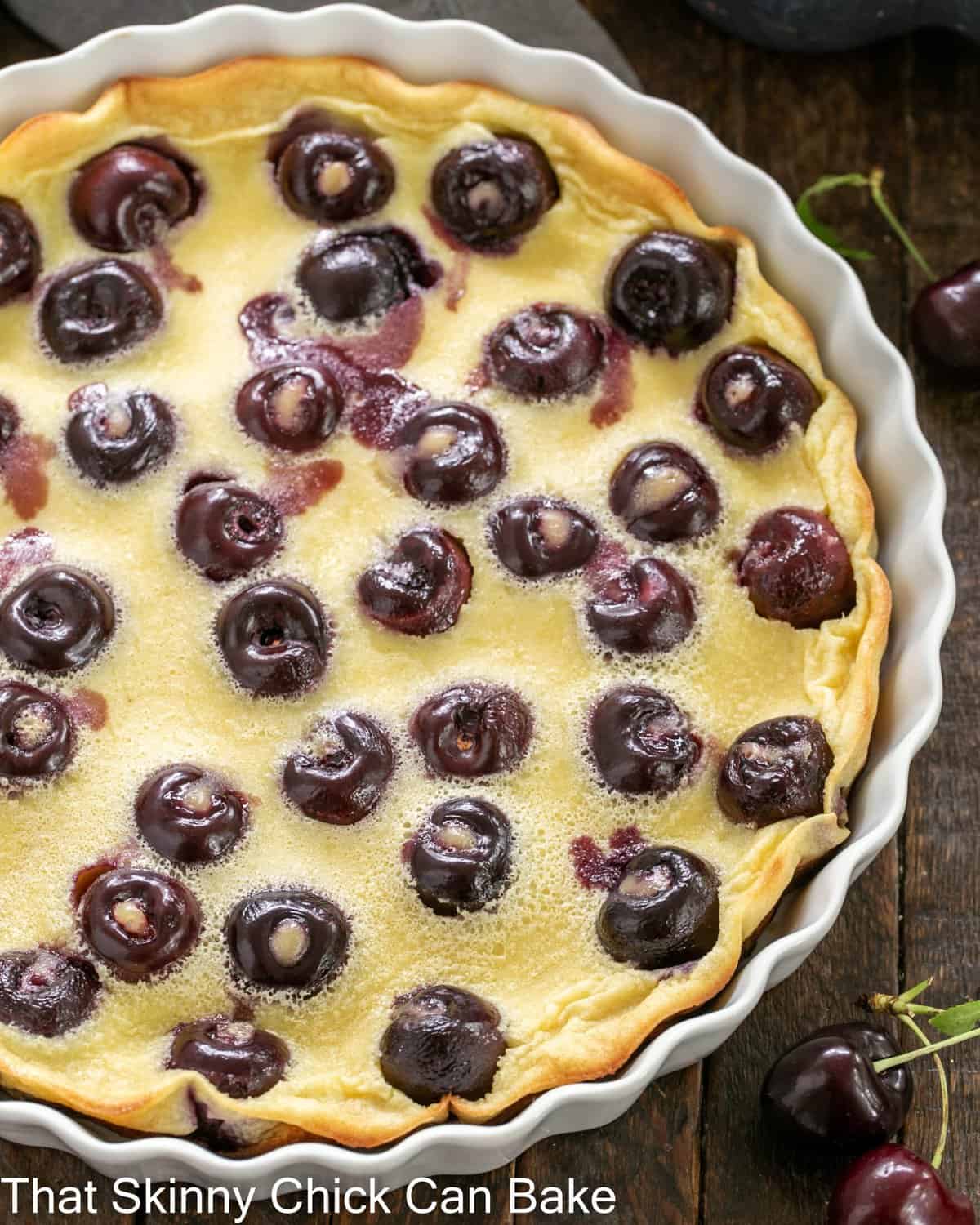 Overhead view of cherry clafoutis in a shallow white souffle dish.