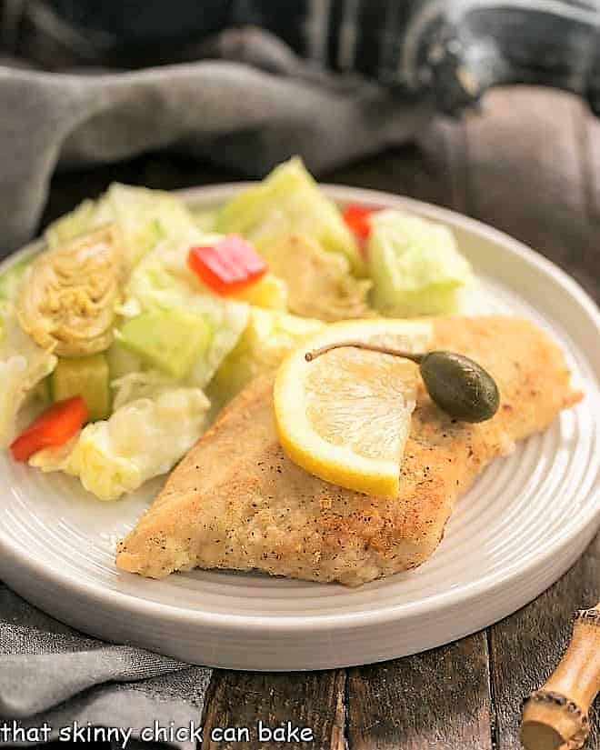 Easy Skillet Chicken Piccata on a round white plate with a lettuce salad.