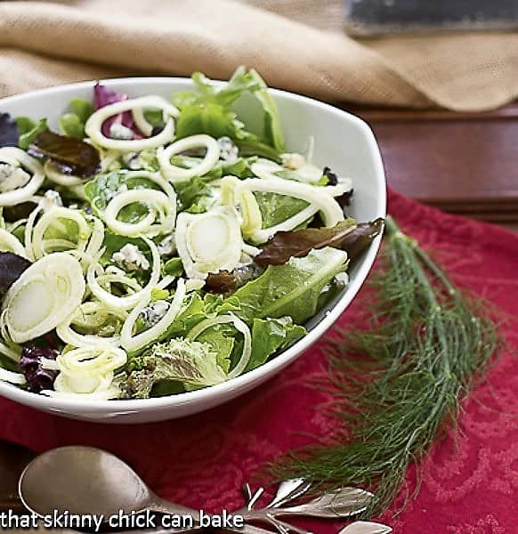 Fennel and Gorgonzola Salad in a white salad bowl in a serving bowl with a fennel frond