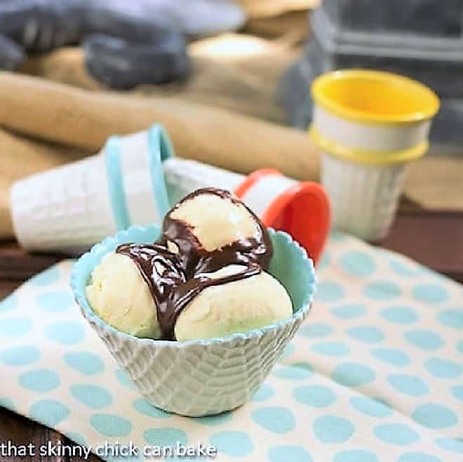 Vanilla Bean Ice Cream - Simple, luscious vanilla bean ice cream flavored with real vanilla paste Vanilla Bean Ice Cream in a cone textured ice cream bowl topped with hot fudge sauce.