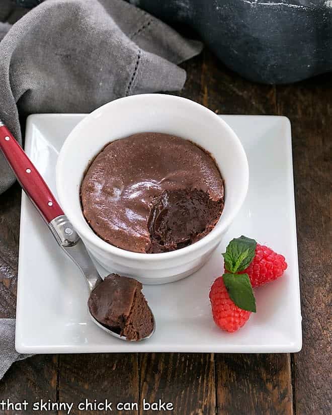 Warm Individual Chocolate Cheesecake Recipe - a rich luscious individual dessert for chocolate and cheesecake lovers alike! Individual chocolate cheesecake in a white ramekin on a square white plate with a spoonful removed