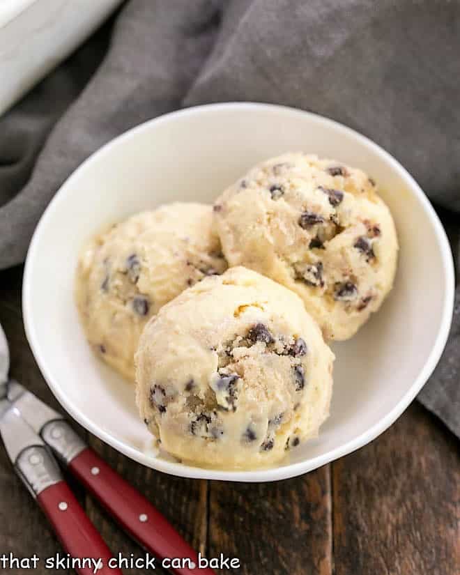 Overhead view of 3 scoops of cookie dough ice cream in a white bowl.