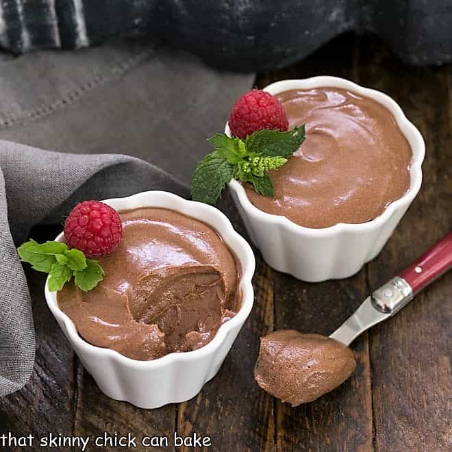 2 small white dishes of chocolate mousse with a raspberry and mint garnish