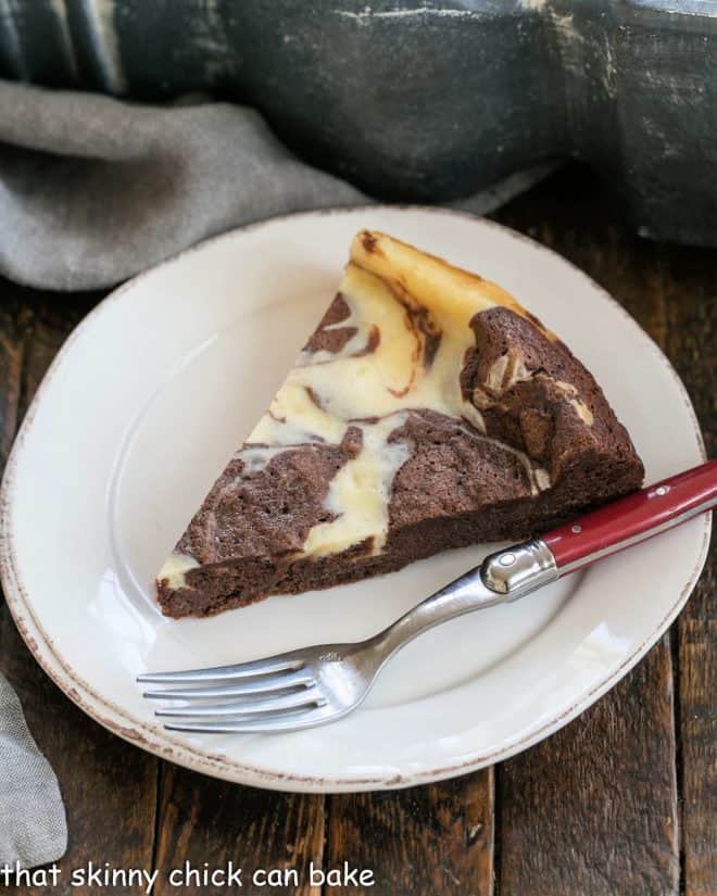 overhead view of a slice of marbled flourless chocolate cake on a white dessert plate with a red handled fork.