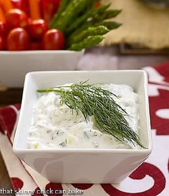 Tzatziki - a versatile Greek yogurt sauce filled with fresh herbs, garlic and cucumber Greek Tzatziki in a white square bowl