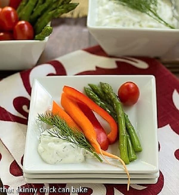 Tzatziki Dip - a versatile Greek yogurt sauce filled with fresh herbs, garlic and cucumber Tzatziki on a stack of white plates with fresh vegetables