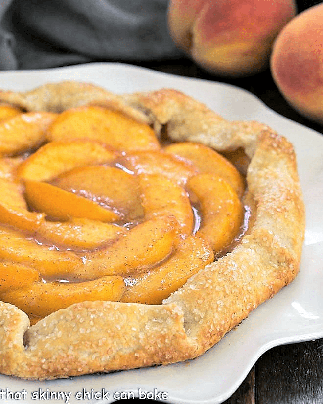 Galette Recipe with Fresh Peaches - a marvelous dessert with all the glorious flavors of a homemade pie Partial closeup view of a peach galette on a white serving plate.