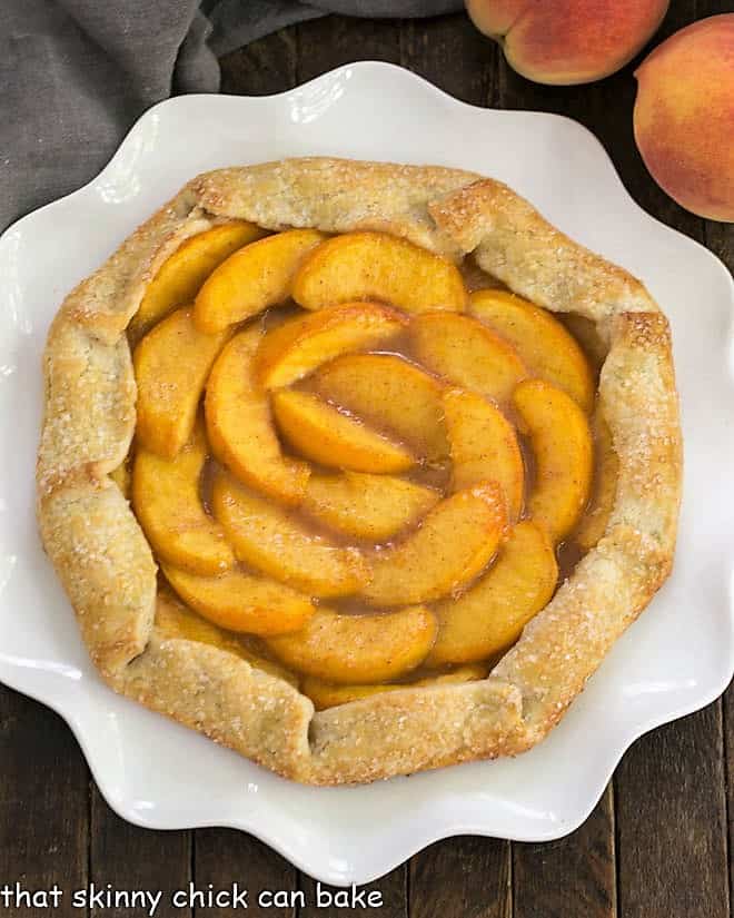 Rustic Peach Galette - a marvelous dessert with all the glorious flavors of a homemade pie Overhead view of a Rustic Peach Galette on a ruffled white serving plate.