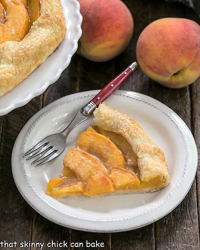 Rustic Peach Tart - a marvelous dessert with all the glorious flavors of a homemade pie Slice of peach galette on a white plate with a red handle fork.