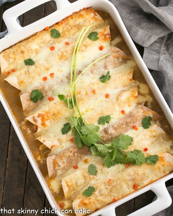 Overhead view of Cheesy Chicken Enchiladas in a white casserole dish with a garnish of cilantro.