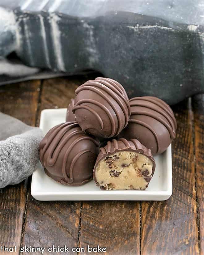 Stack of cookie dough truffles on a square white plate.