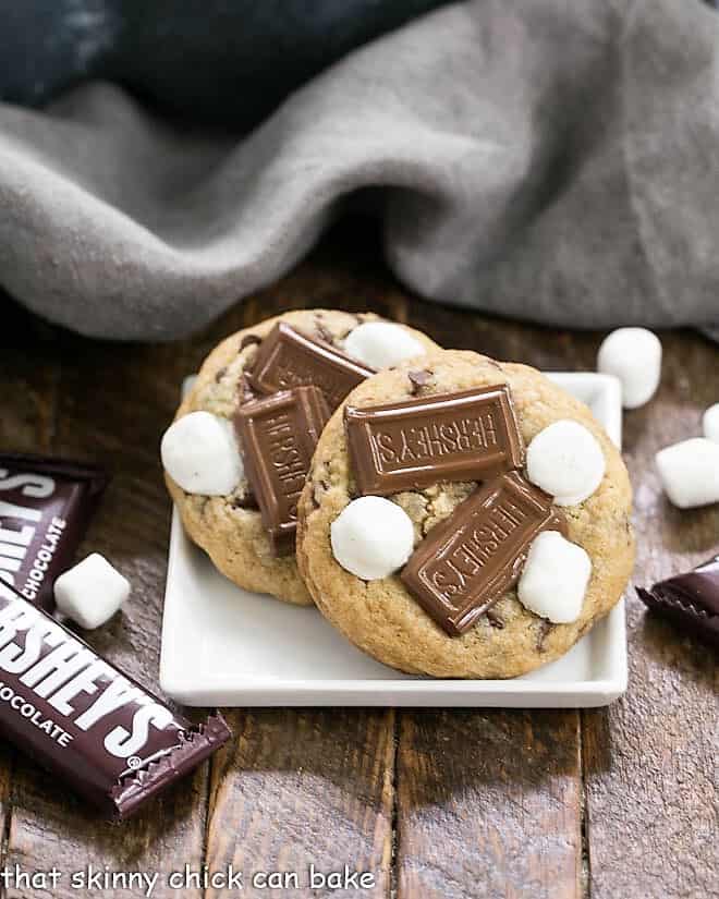 S'mookies AKA Gooey S'mores Cookies on a square white plate with mini Hershey bars.