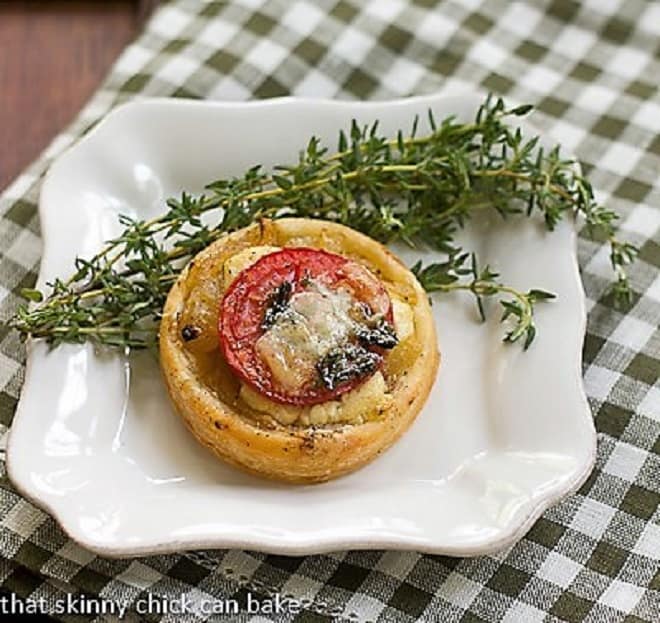 Tomato and Boursin Tartlets - an elegant appetizer with layers of flavor over puff pastry rounds Tomato and Boursin Tartlet on a square white plate with fresh thyme.