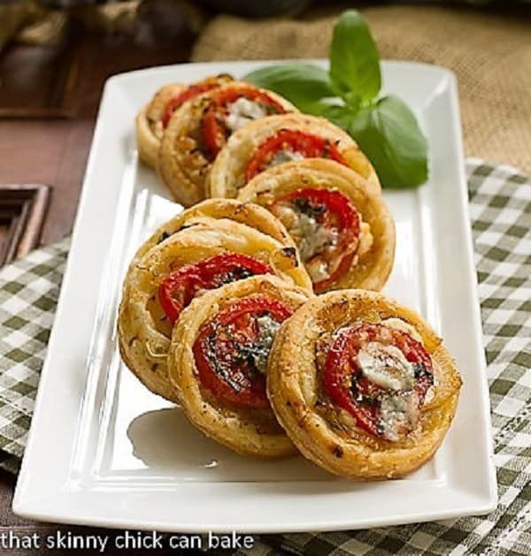 Tomato and Boursin Tartlets - an elegant appetizer with layers of flavor over puff pastry rounds Tomato and Boursin Tartlets on a white ceramic tray.