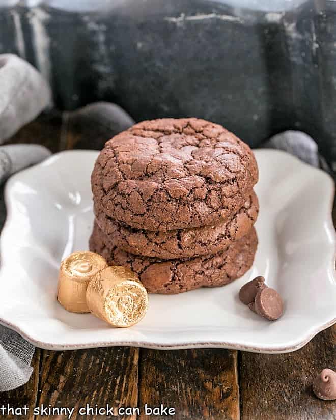 A stack of brownie cookies on a square white plate.